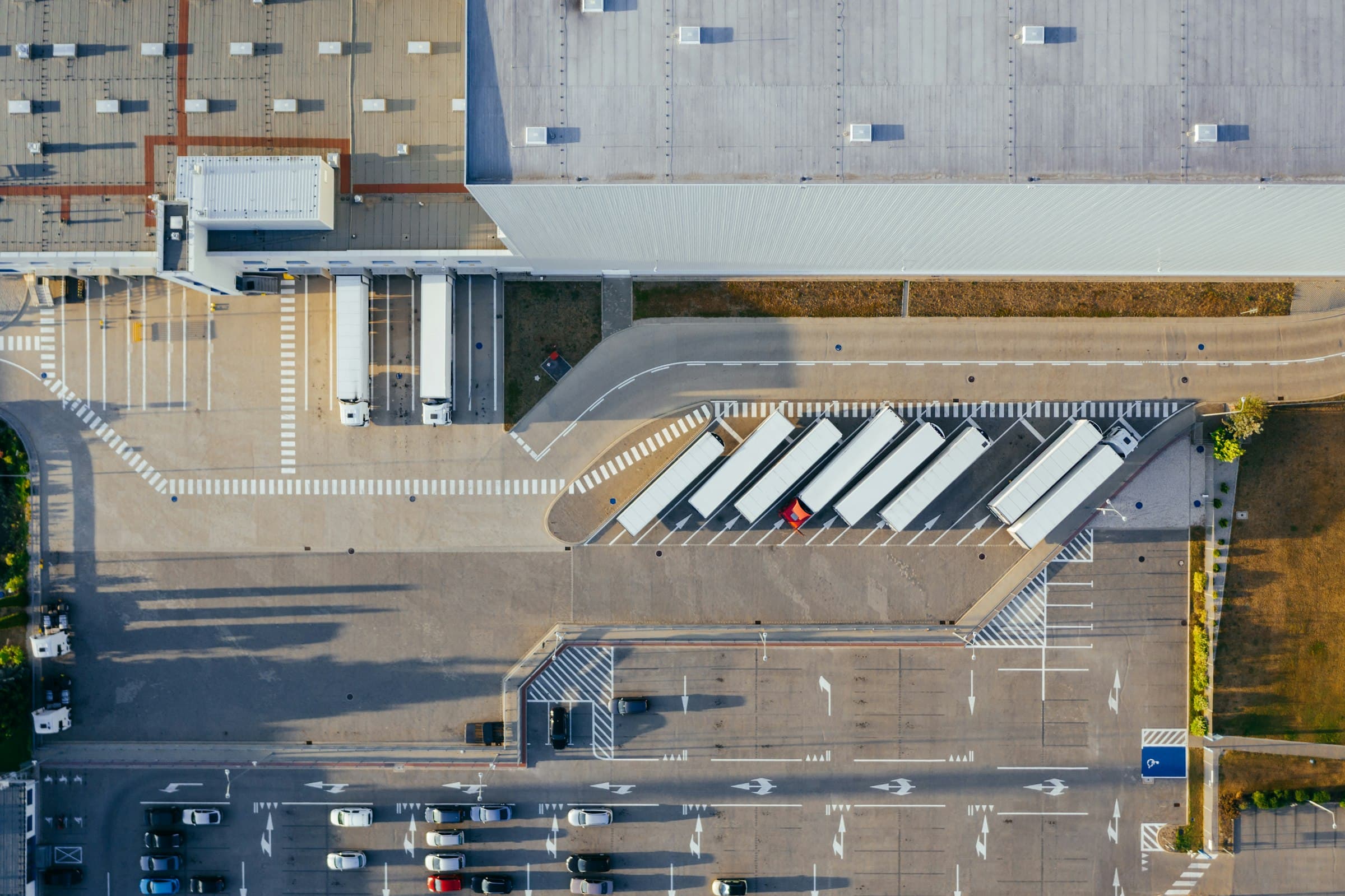 Aerial view of a freight dispatch yard, trailers lined up at the loading dock in early morning light